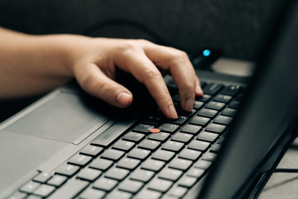 Hands typing on laptop keyboard representing content writing and automation workflow