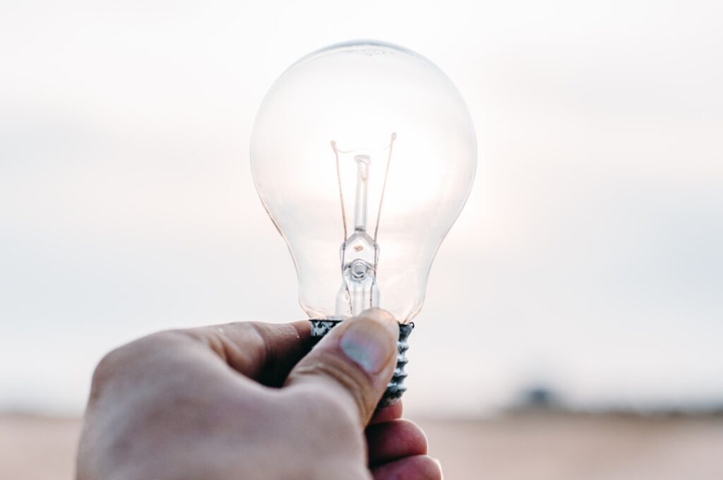 Person holding illuminated light bulb representing key insights and ideas