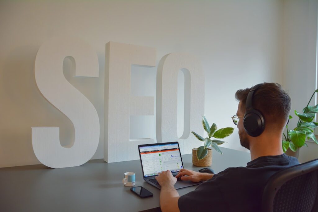 Professional working on SEO optimization at computer with large SEO letters in background, representing local search marketing