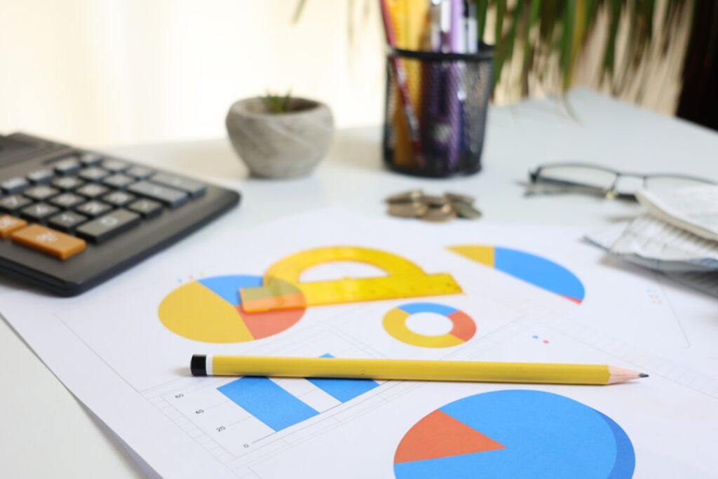 Business desk with colorful charts, calculator and pencil showing cost analysis and budget planning