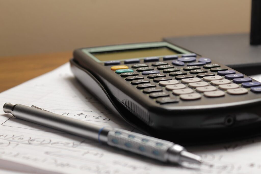 Calculator and pen on financial documents representing cost analysis and budget planning