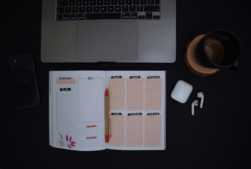 Weekly workflow planning setup with laptop, weekly planner, and coffee on desk