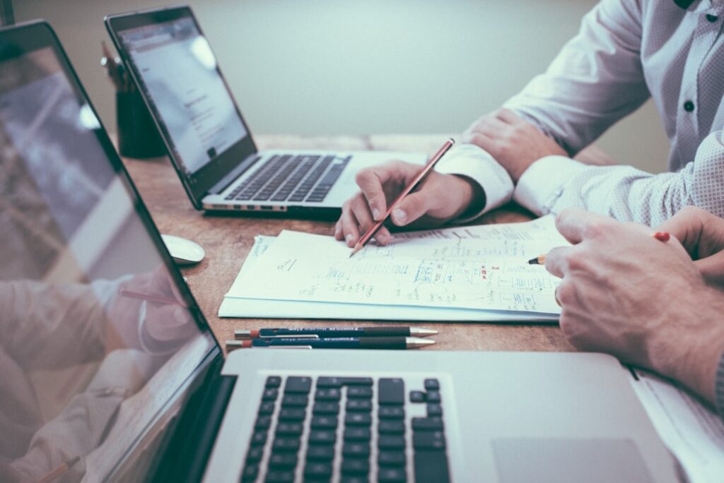 Business professionals collaborating around a table with laptops and papers, illustrating human expertise and strategic decision-making in content strategy