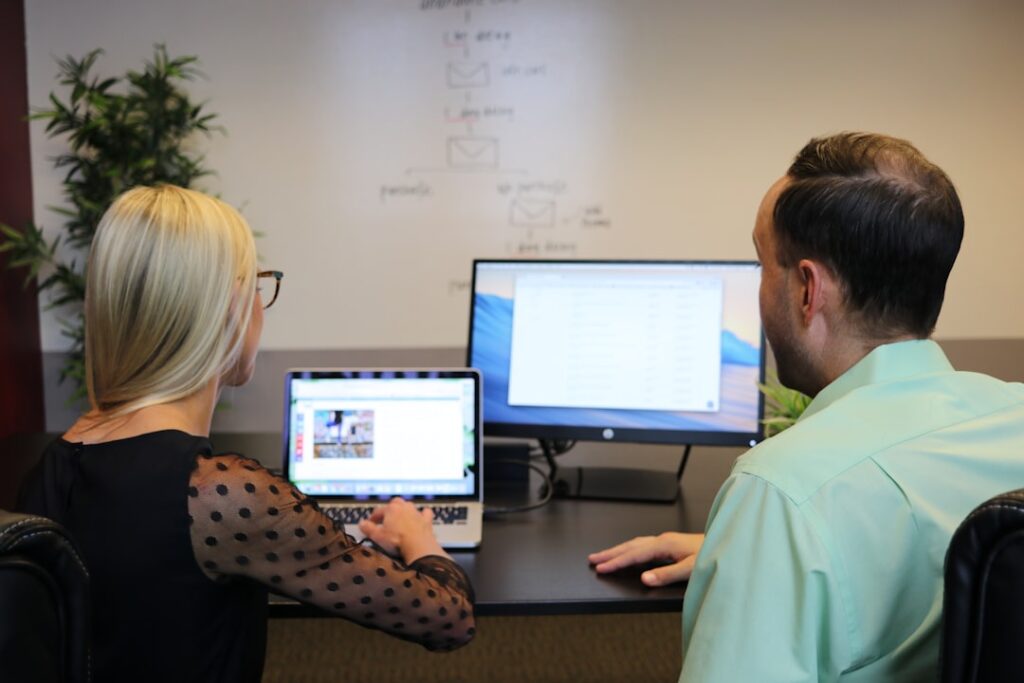 Two team members reviewing a WordPress website on dual monitors, evaluating CMS integration options