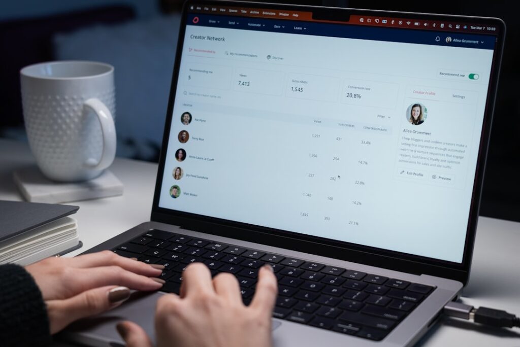 Hands typing on a laptop showing an email marketing platform dashboard with contact metrics, representing the kind of interface small business owners navigate when using marketing automation tools.