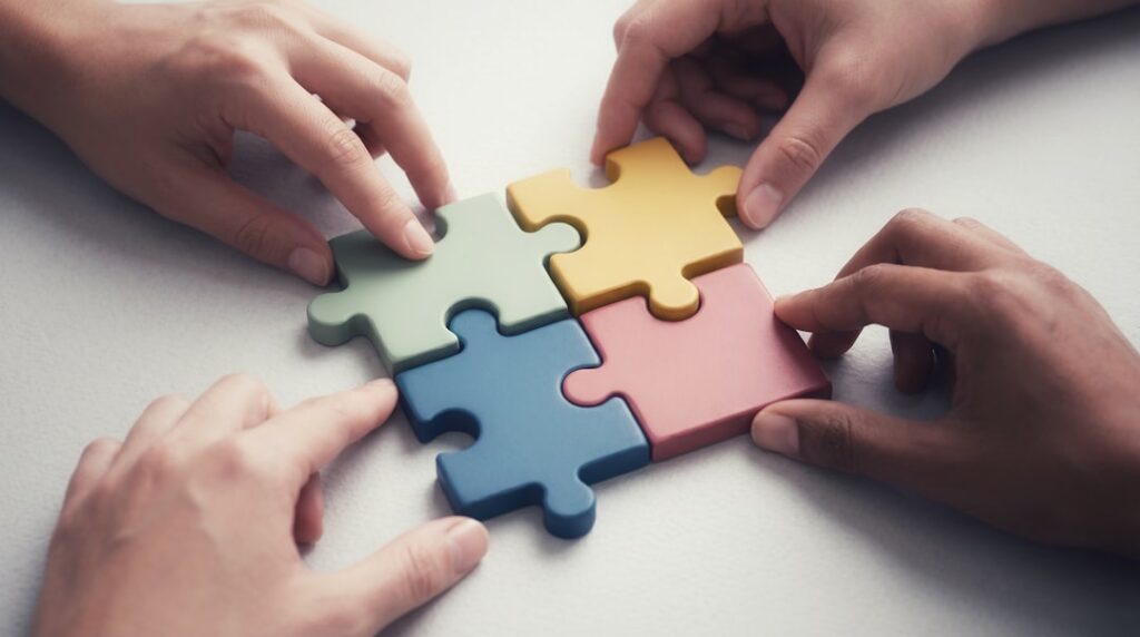 Hands working together to assemble colorful puzzle pieces, representing the collaborative workflow between humans and AI in content creation