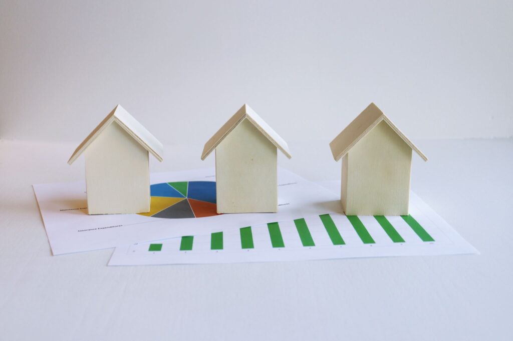 Wooden model houses placed on real estate market data charts and graphs