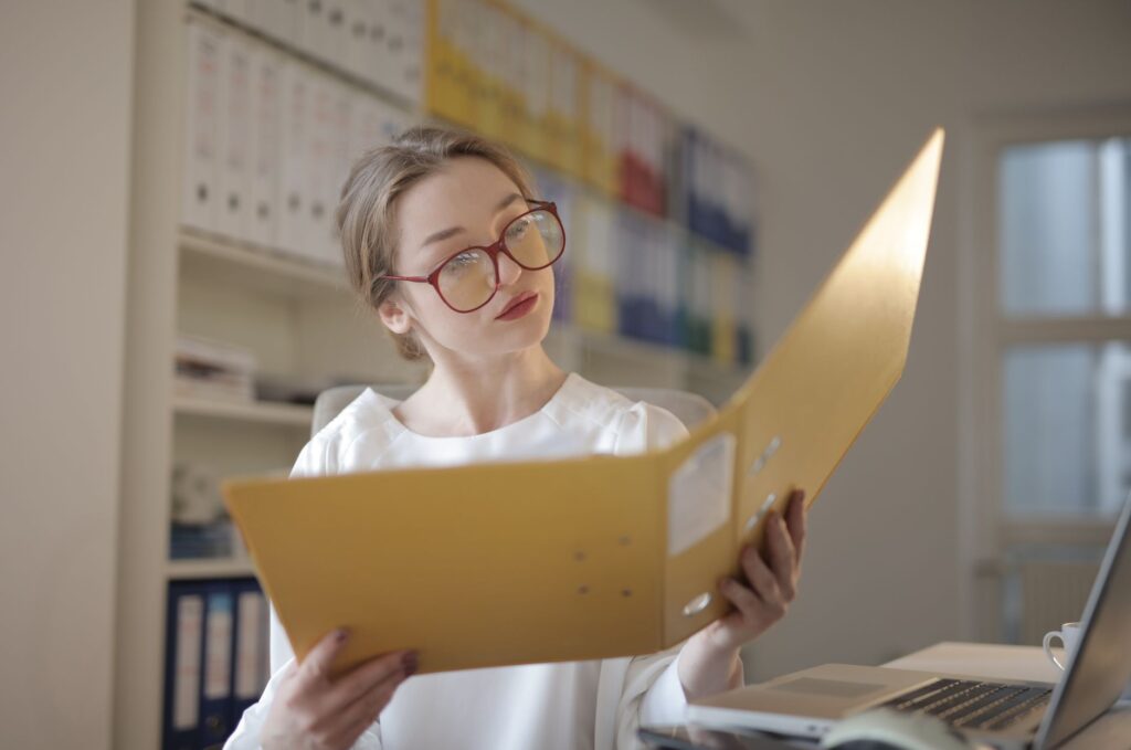Accountant reviewing client financial documents and folders in a professional office setting