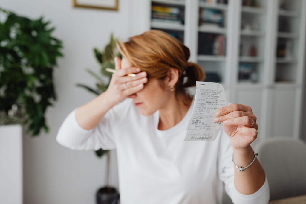 Business owner stressed reviewing expensive agency invoices and receipts at desk