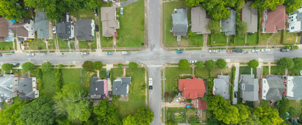 Aerial view of a suburban neighborhood intersection with homes and tree-lined streets