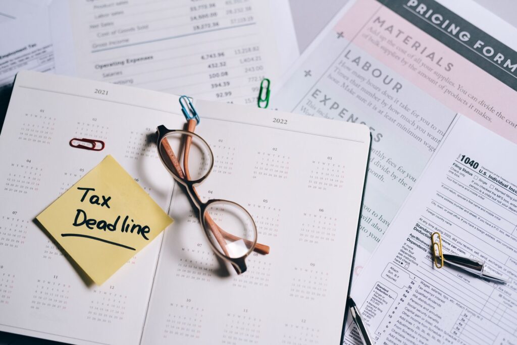 Calendar marked with Tax Deadline sticky note alongside financial documents and glasses, illustrating accounting seasonality