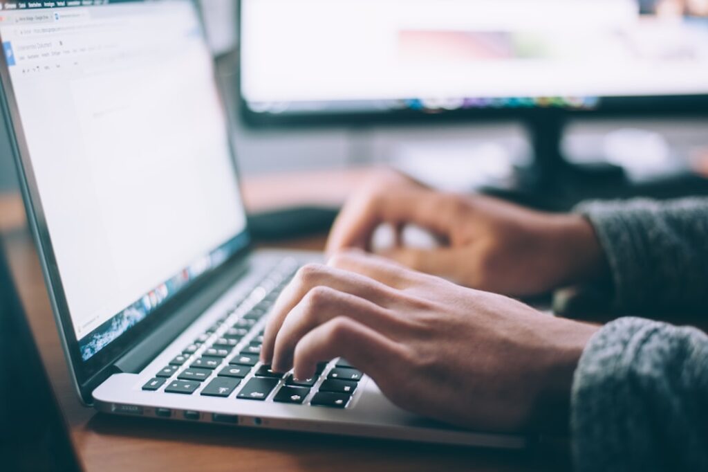 Person typing on a laptop keyboard, creating written content