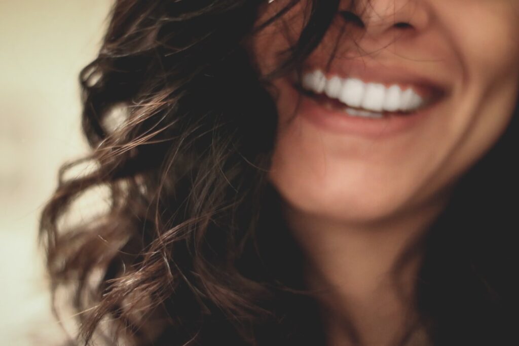 Close-up of a woman with a bright, confident smile — representing cosmetic dentistry, teeth whitening, and dental implant results