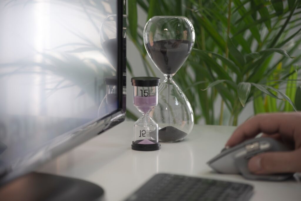 Hourglass sitting on a desk next to a computer mouse, representing the hidden time cost of manual WordPress formatting after using free AI writing tools