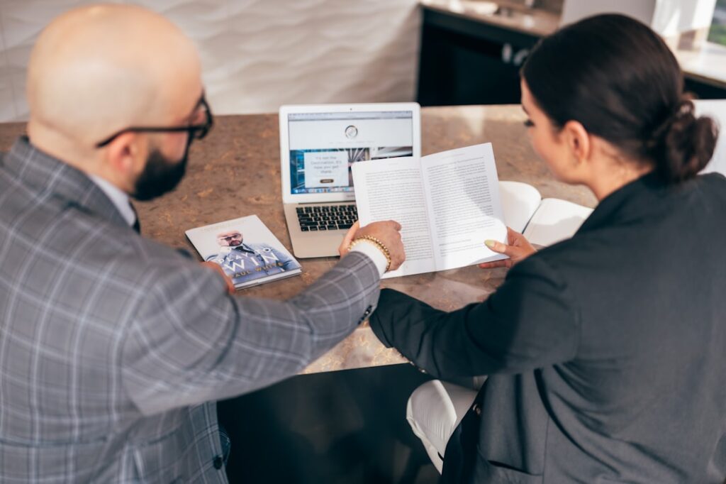 Two business professionals reviewing a document and laptop together, representing agency content retainer review