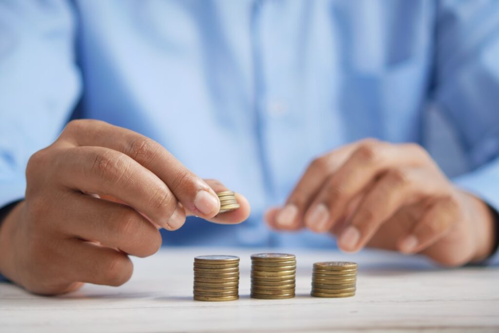 Person comparing stacks of coins representing cost comparison between AI content tools and traditional content agencies