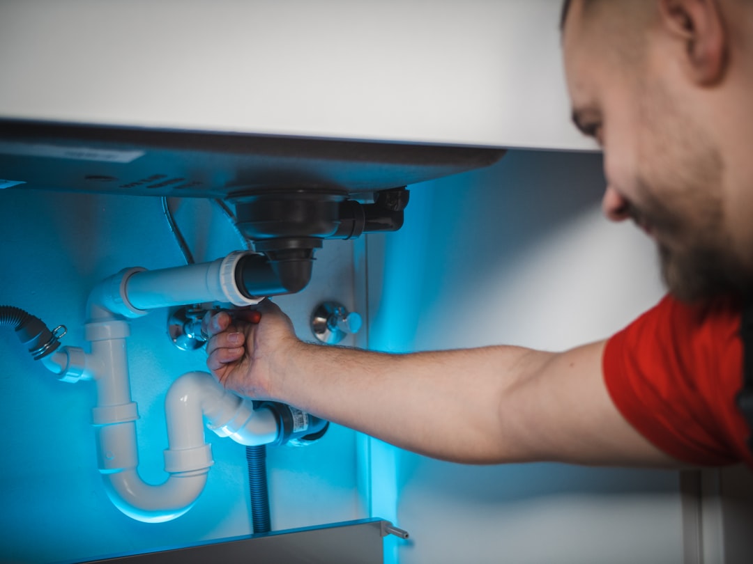 Professional plumber working on under-sink pipe connections