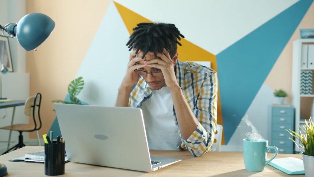 Frustrated business owner stressed at laptop after realizing how much manual work a free AI blog writer leaves behind