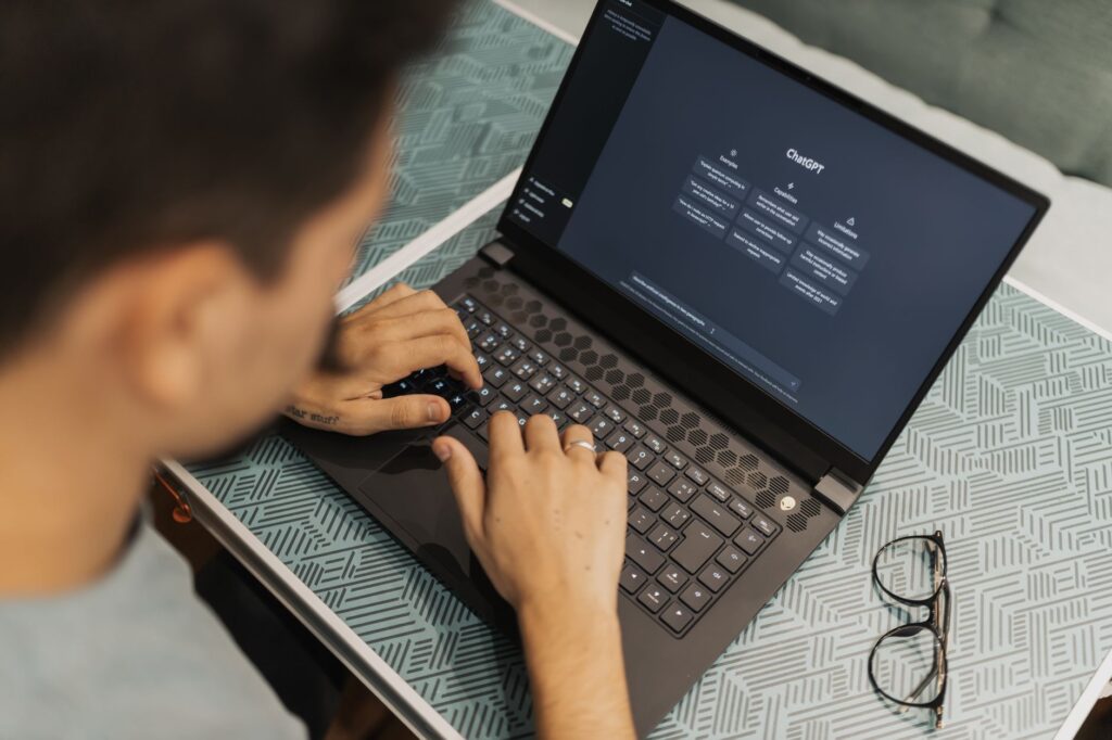 Person using ChatGPT on a laptop, illustrating AI writing tools used alongside SEO content optimization platforms