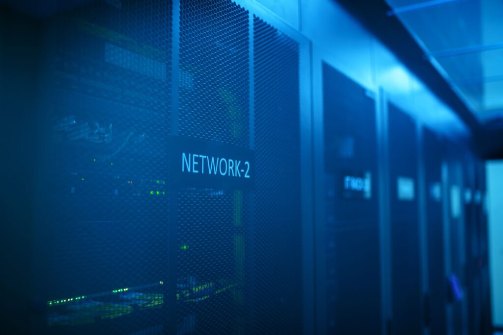 Blue-lit data center server room with network equipment labeled NETWORK-2, representing hosting-level WAF infrastructure