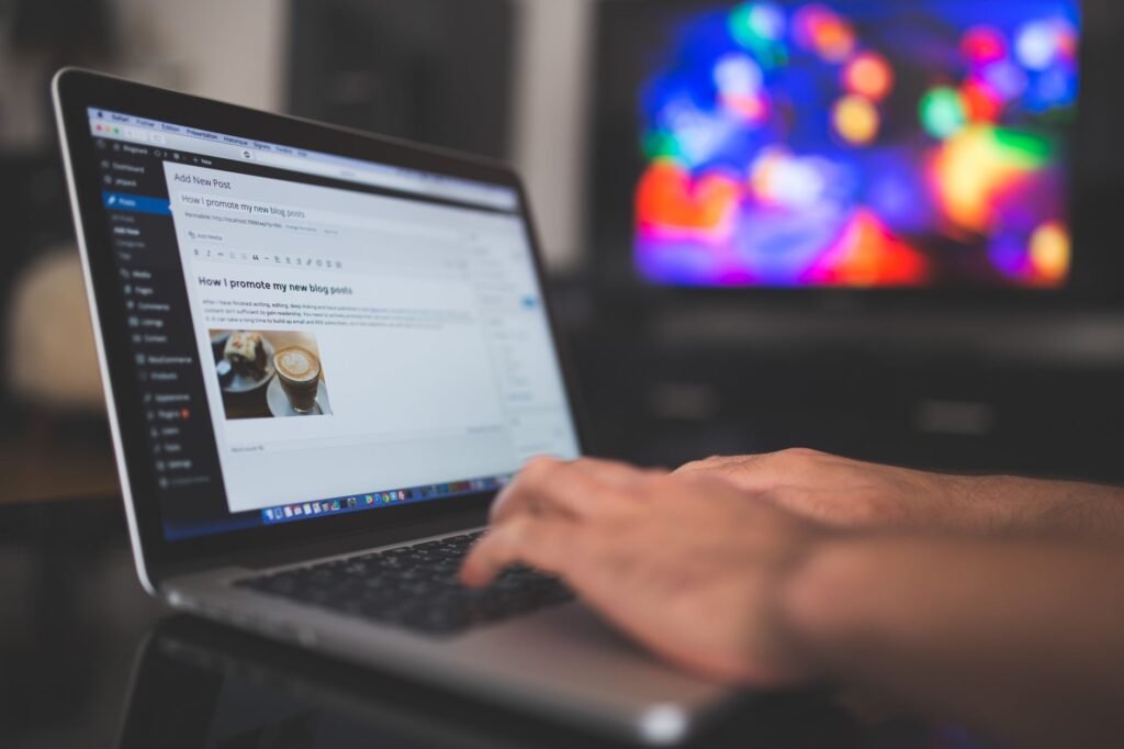Person typing on a laptop with a blog post editor visible on the screen