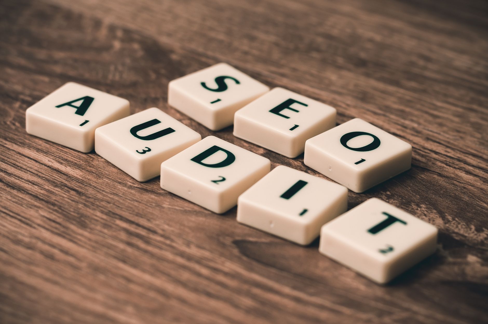 Scrabble tiles spelling SEO Audit on a wooden surface, representing a Yoast SEO checker audit process