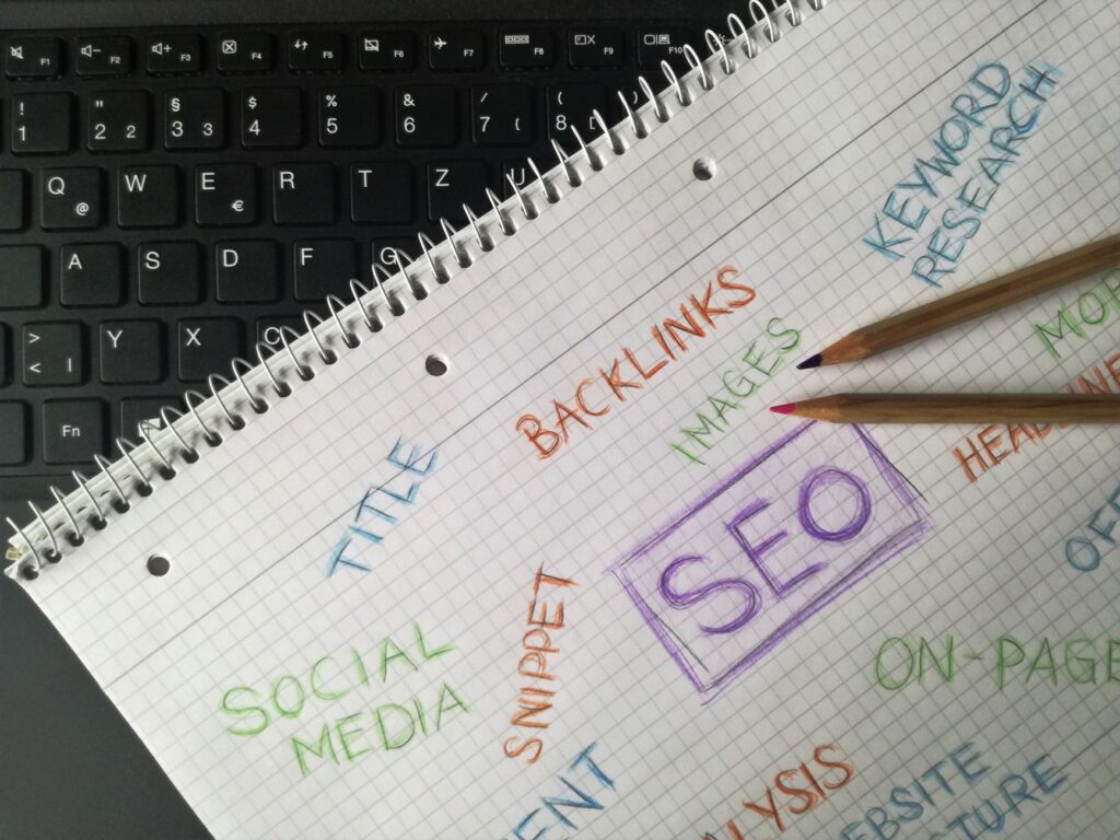 Notebook with handwritten SEO terms including keyword research, backlinks, and on-page optimization, representing content strategy planning for a small business blog.