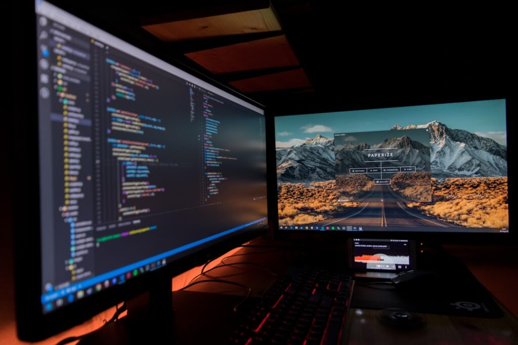 Dual monitor desktop setup with code, representing a power-user desktop app workflow for bulk content production