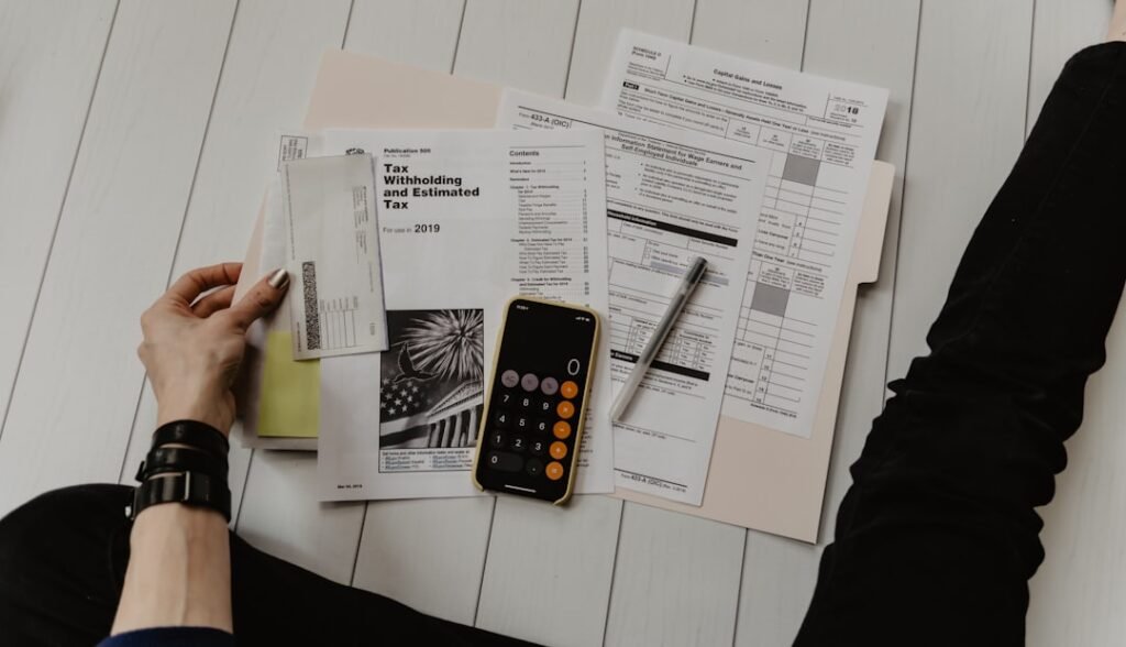 Person reviewing financial documents and using a calculator — calculating the real per-post cost of a content agency retainer.