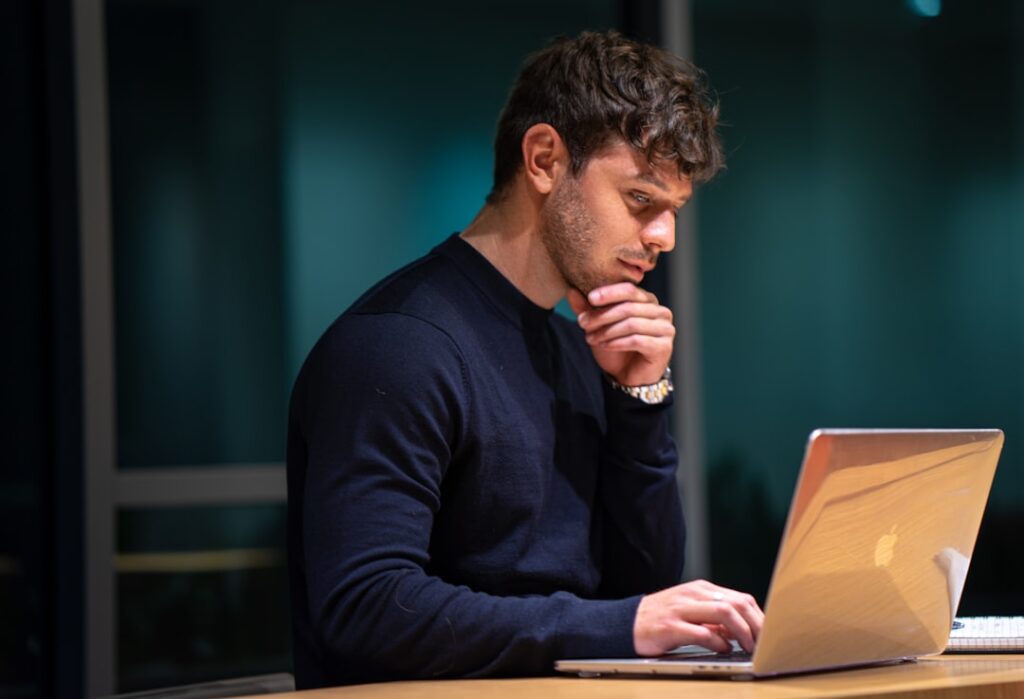 Man carefully reviewing content on a MacBook laptop, scrutinizing what he is reading