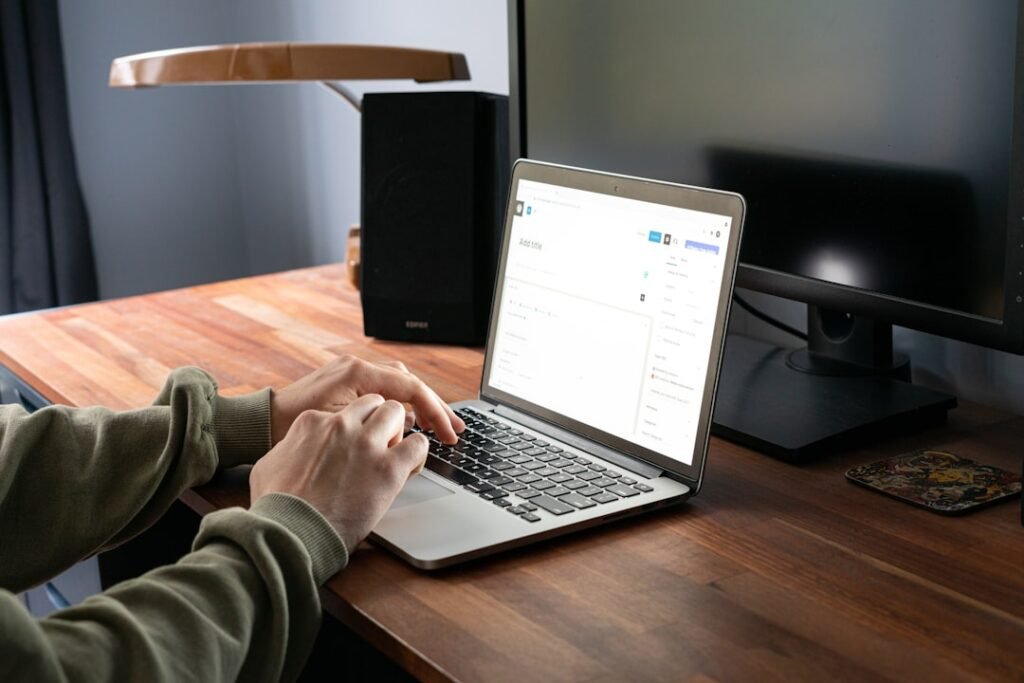 Person using WordPress on a laptop at a desk, representing the post-draft publishing workflow that still requires manual work after Writesonic generates an article