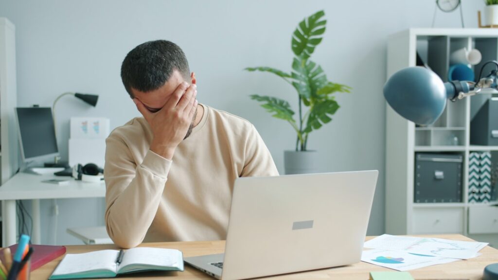 Exhausted marketer at a desk overwhelmed by manual content work and slow workflows.