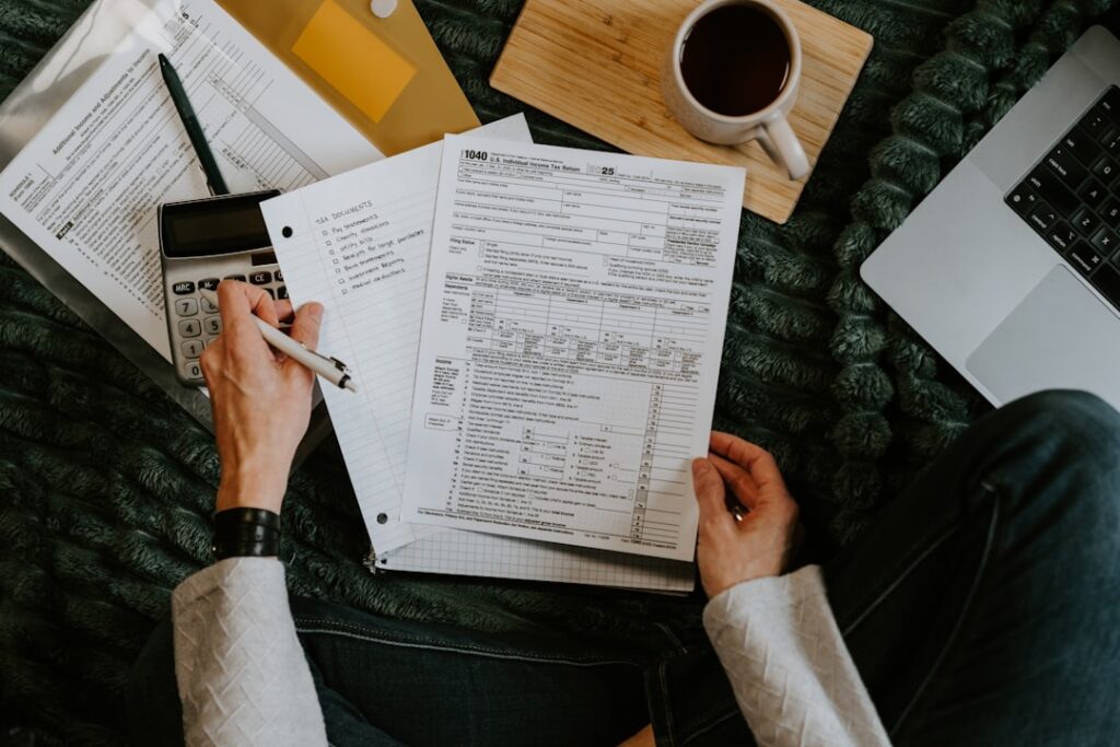 Person reviewing financial documents and cost breakdown with a calculator and laptop, representing the true monthly total cost calculation for a Jasper AI stack.