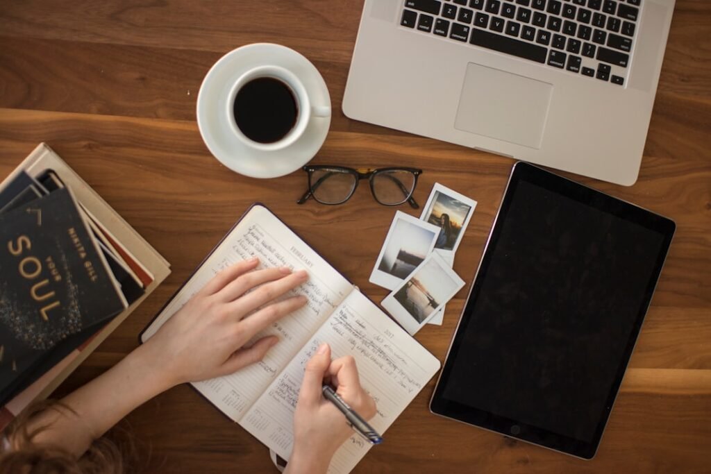 Writer working at a desk with notebook, laptop, and tablet, illustrating the real labor cost breakdown behind every blog post.