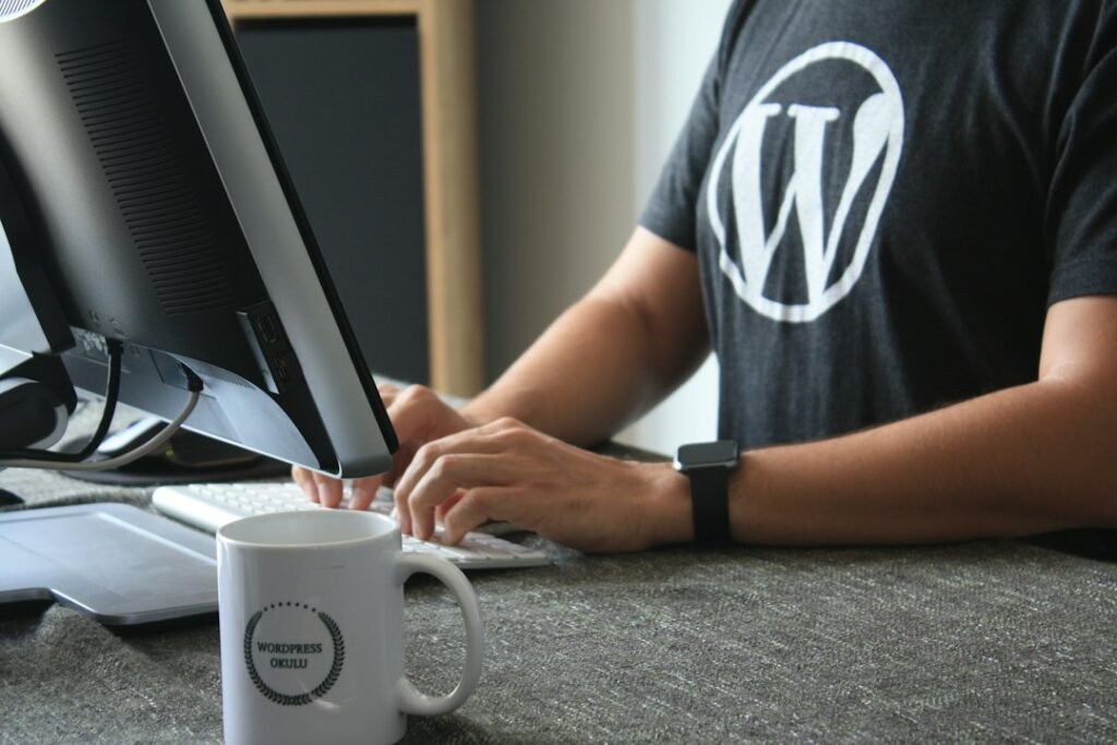 WordPress developer wearing a WordPress logo t-shirt working at a desktop computer