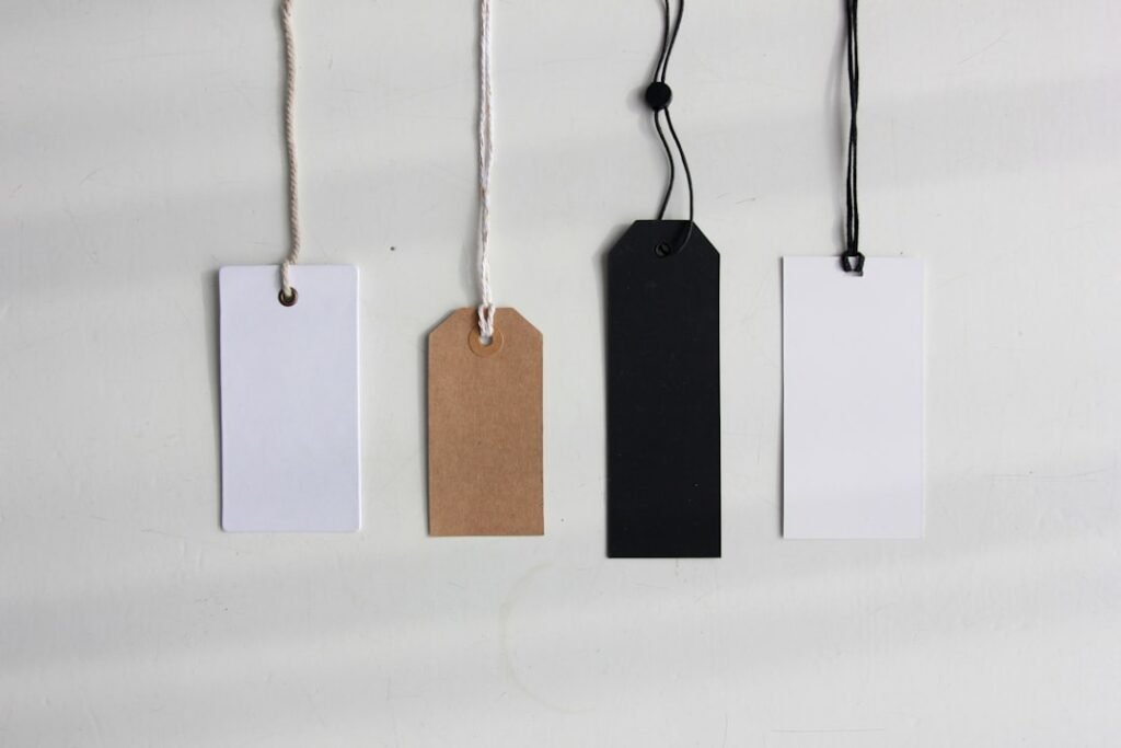 Four paper product tags hanging on strings representing Etsy listing tags and SEO labels