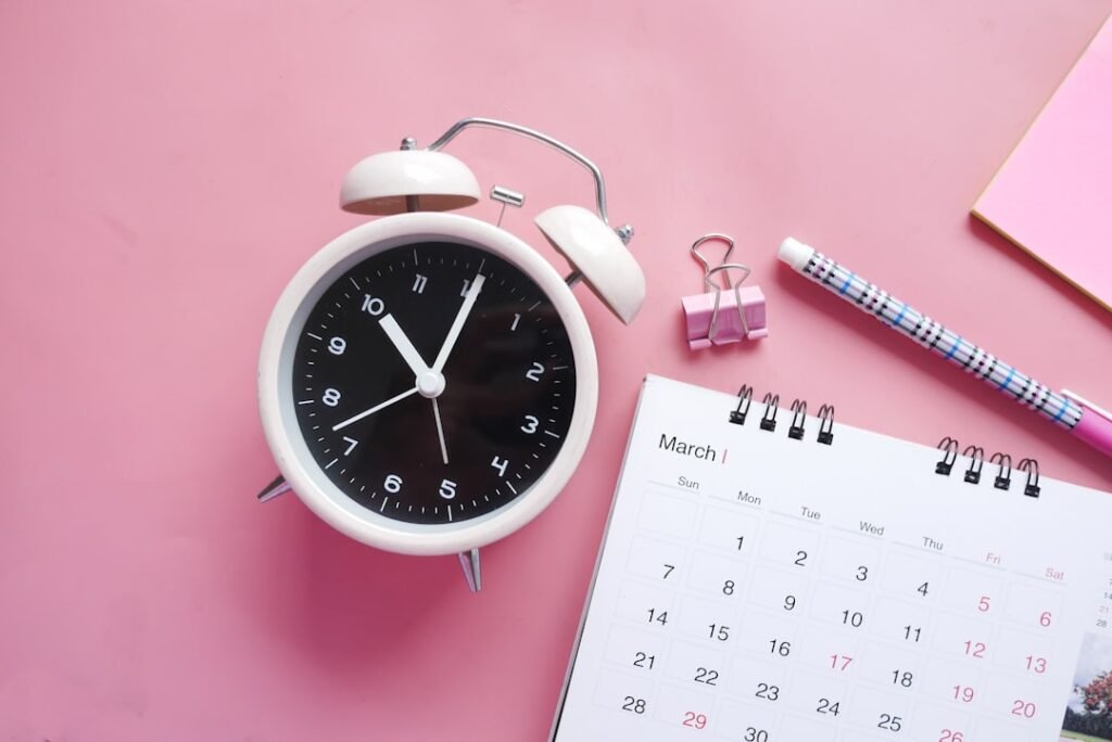 Alarm clock next to a desktop calendar illustrating a scheduling deadline.