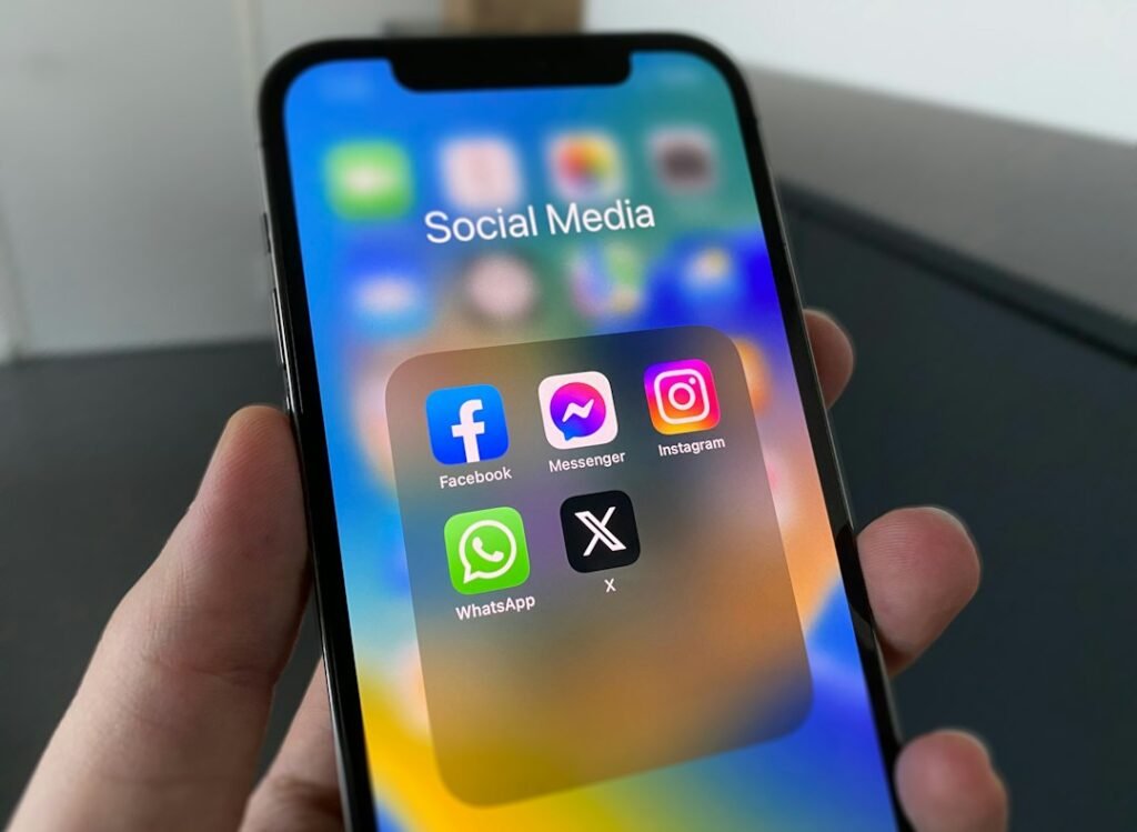 iPhone displaying a Social Media folder with Facebook, Messenger, Instagram, WhatsApp, and X app icons