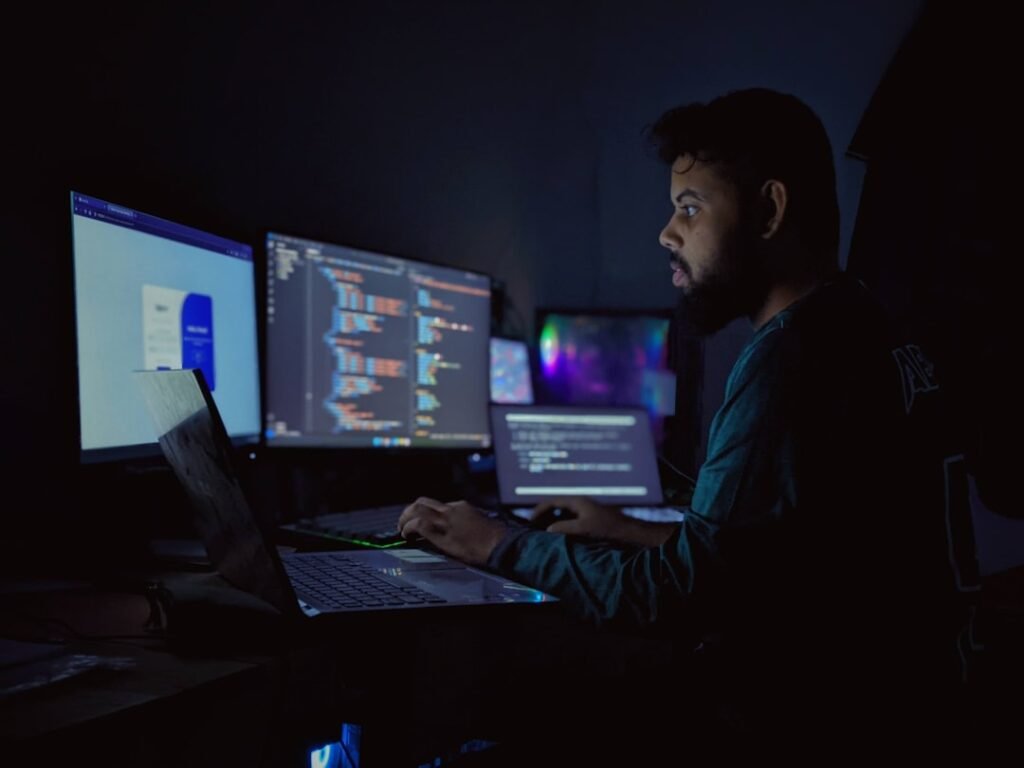 A software developer working at night with multiple screens showing code, representing a local development environment setup