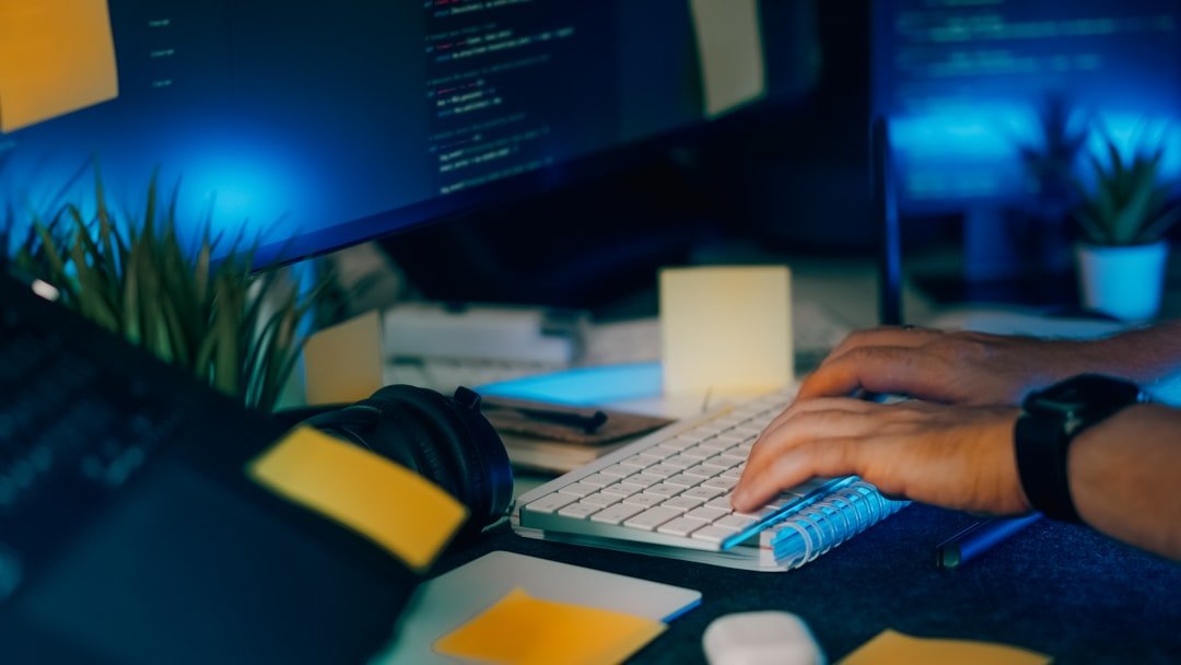 Developer hands typing on keyboard in dark office, representing AI content creation workflow. Photo by Unsplash.
