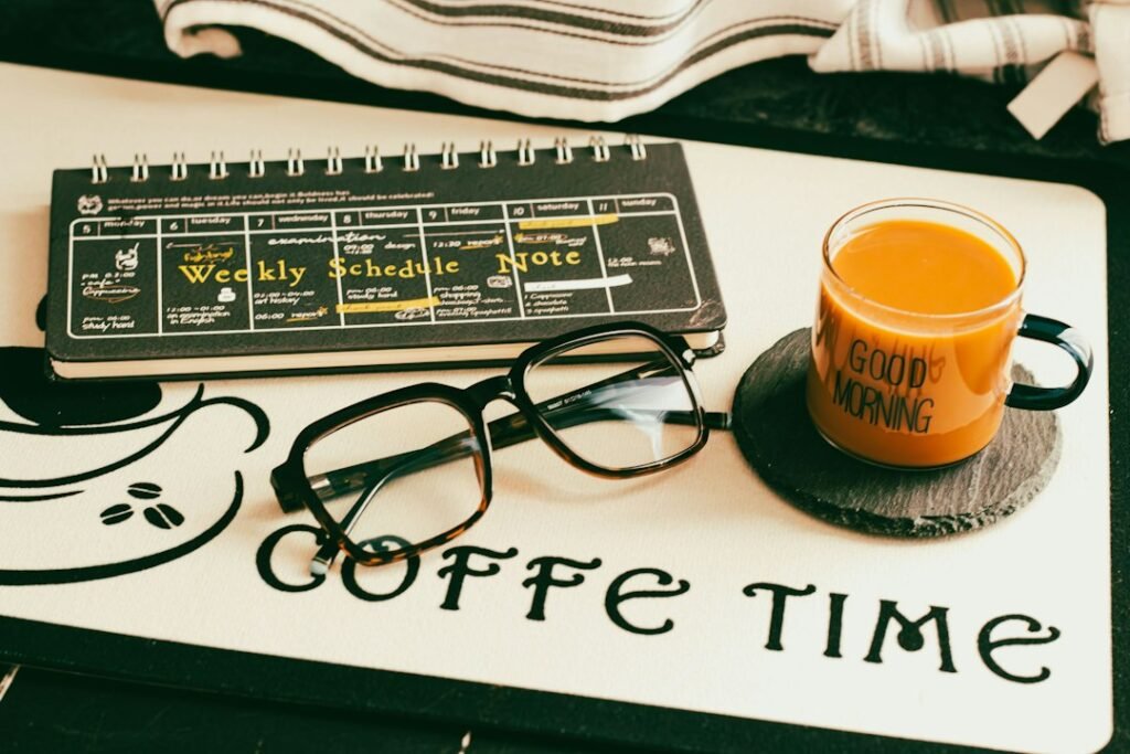 Weekly schedule planner notebook with glasses and a Good Morning coffee mug on a desk, representing a Monday morning SEO workflow routine