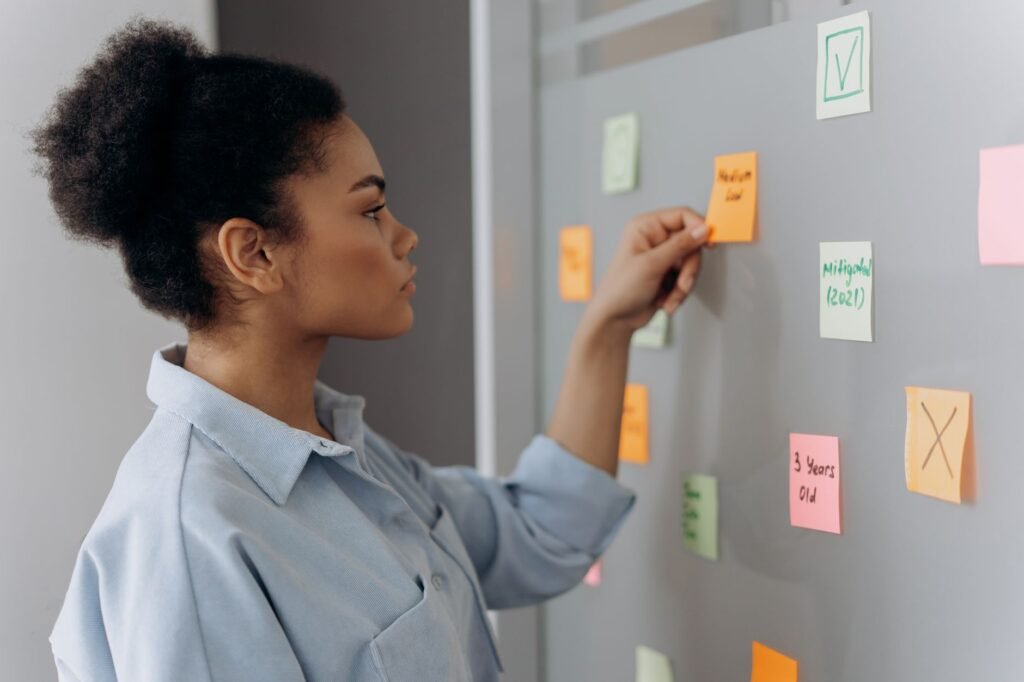 Woman organizing and prioritizing sticky notes on a whiteboard, representing a content audit and prioritization framework