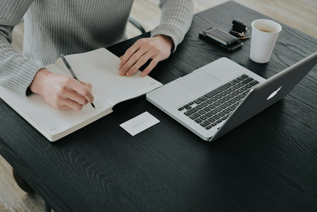 Solo founder writing content strategy notes alongside a laptop — planning a sustainable blogging system