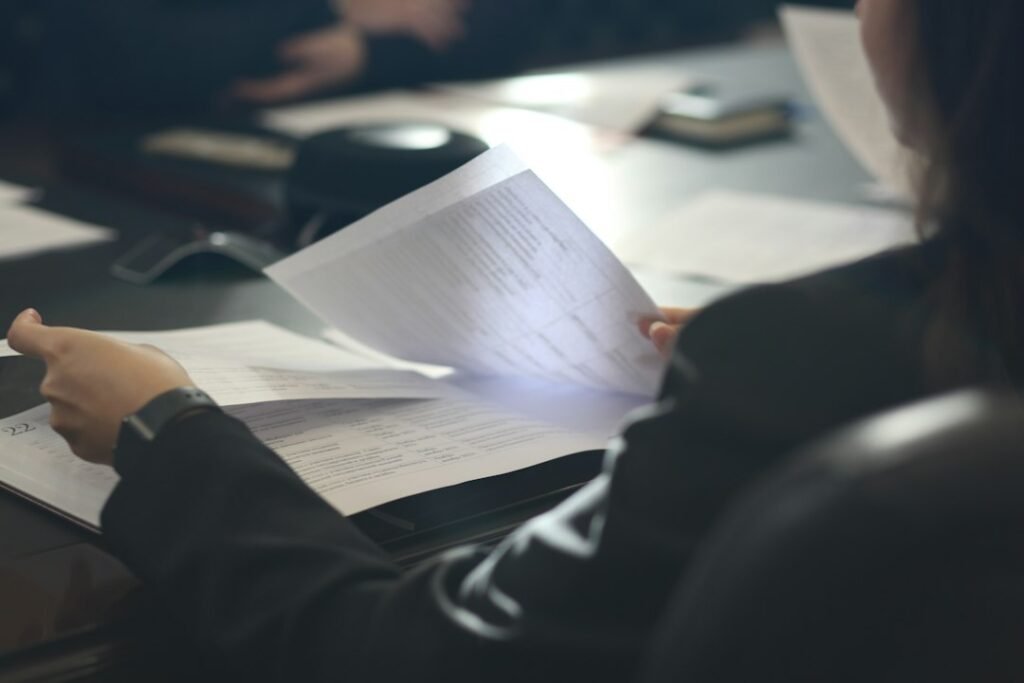 A person carefully reviewing printed documents at a desk — representing the editorial review and fact-checking step that E-E-A-T demands before publishing AI-assisted content.