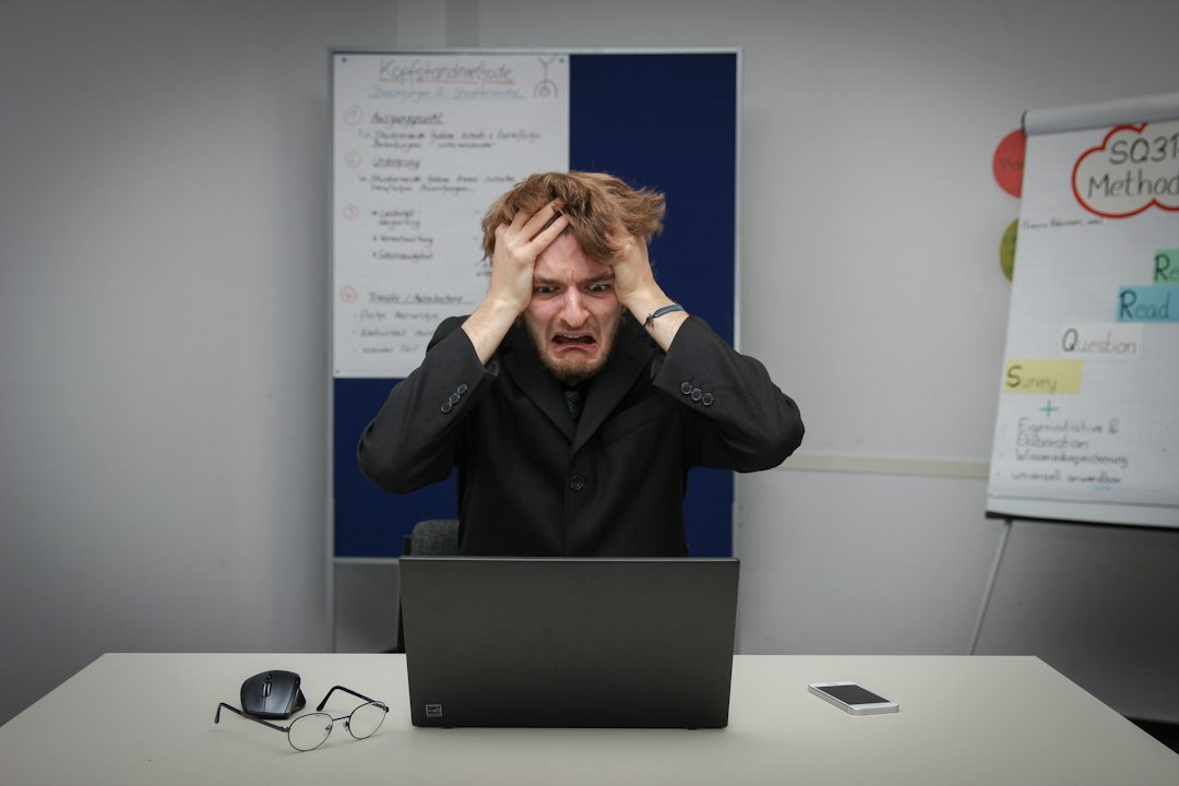 Frustrated business owner with hands on head staring at laptop screen, representing the experience of evaluating SEO company costs. Photo by Unsplash.