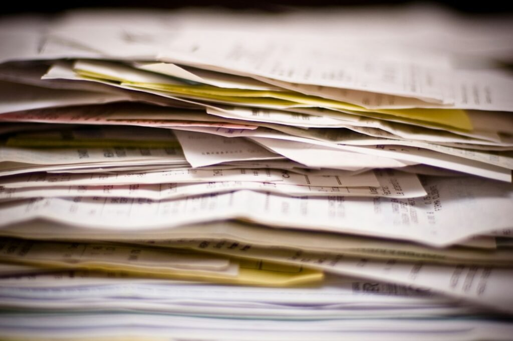 Towering stack of invoices and receipts illustrating hidden labor costs that accumulate in content production