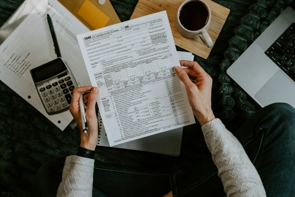 Person reviewing financial documents and forms with a calculator and coffee on the desk, representing hidden subscription costs